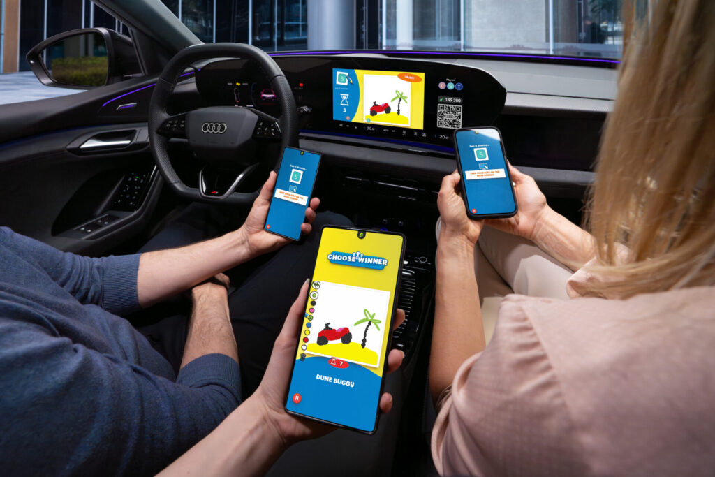 A game from the AirConsole gaming platform runs on the touch display in an Audi. The driver, front passenger, and a person in the back seat each hold a smartphone in front of the display. They use the smartphones as controllers to play the game.
